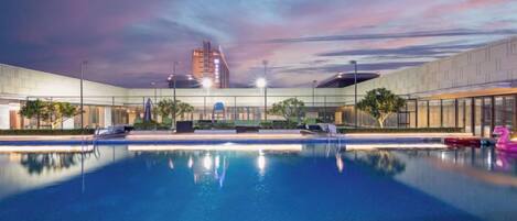A swimming pool with a view of a building and a sunset.