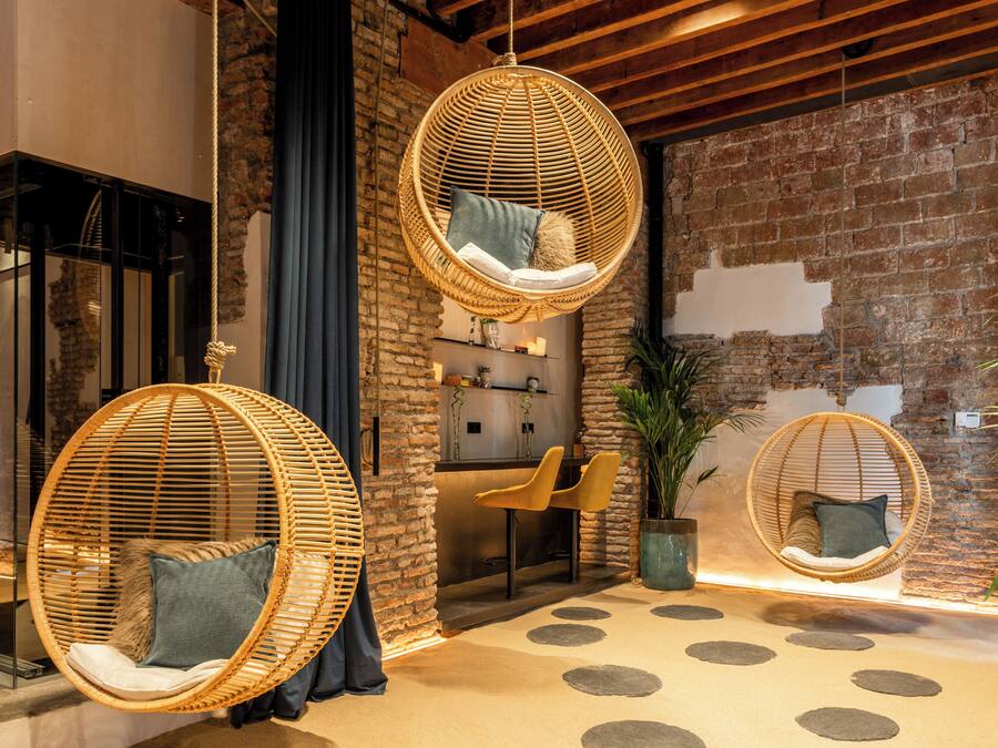 A modern interior with hanging wicker chairs, a brick wall, and a bar area.