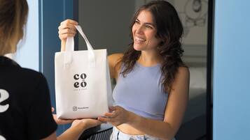 A person holding a white tote bag with 'coeo' branding.