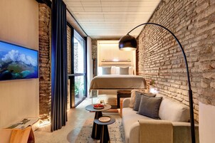 Een moderne hotelkamer met een groot bed, een bank, een eettafeltje en een aan de muur bevestigde televisie.