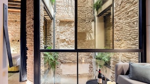 Una habitación moderna con un amplio ventanal con vistas a un patio de piedra.