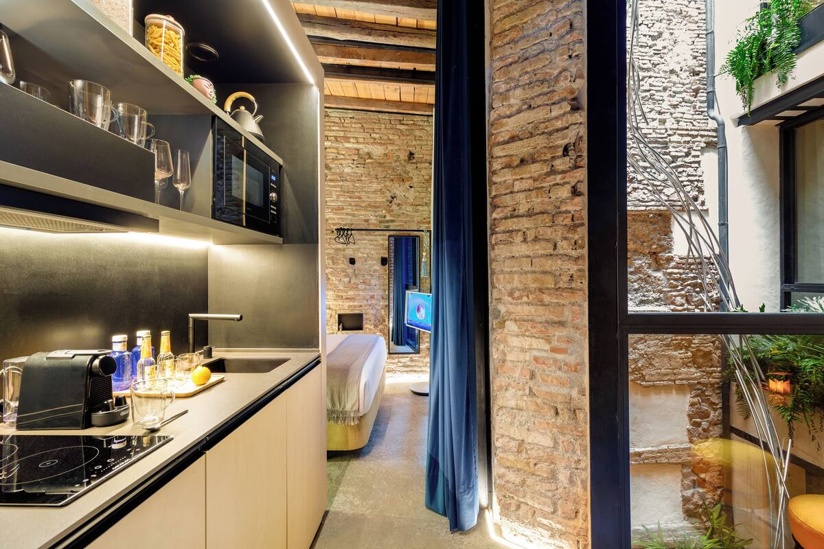 A modern kitchen with a built-in stove, wine glasses, and a coffee machine.