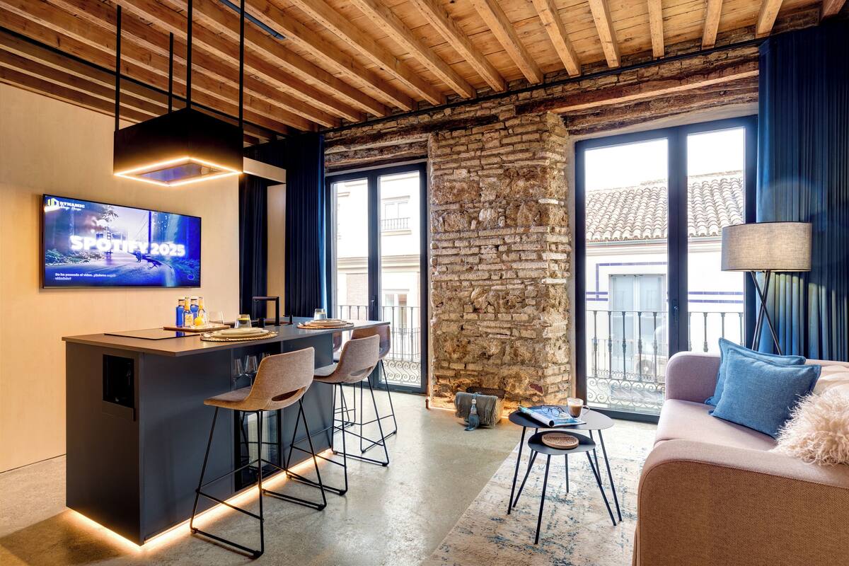 A modern kitchen with a bar area, stone wall, and large windows.