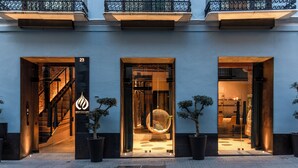 Un edificio moderno con tres accesos, cada uno con puerta de cristal y un árbol en maceta.