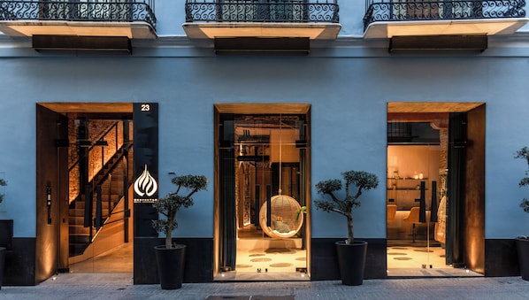 Un bâtiment moderne doté de trois entrées, chacune ayant une porte en verre et un arbre en pot.