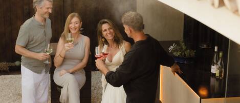 A group of people socializing at an outdoor bar area with a modern design, including a counter and seating.