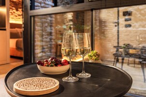 A table with two glasses of white wine, a bowl of fruit, and a decorative plate.