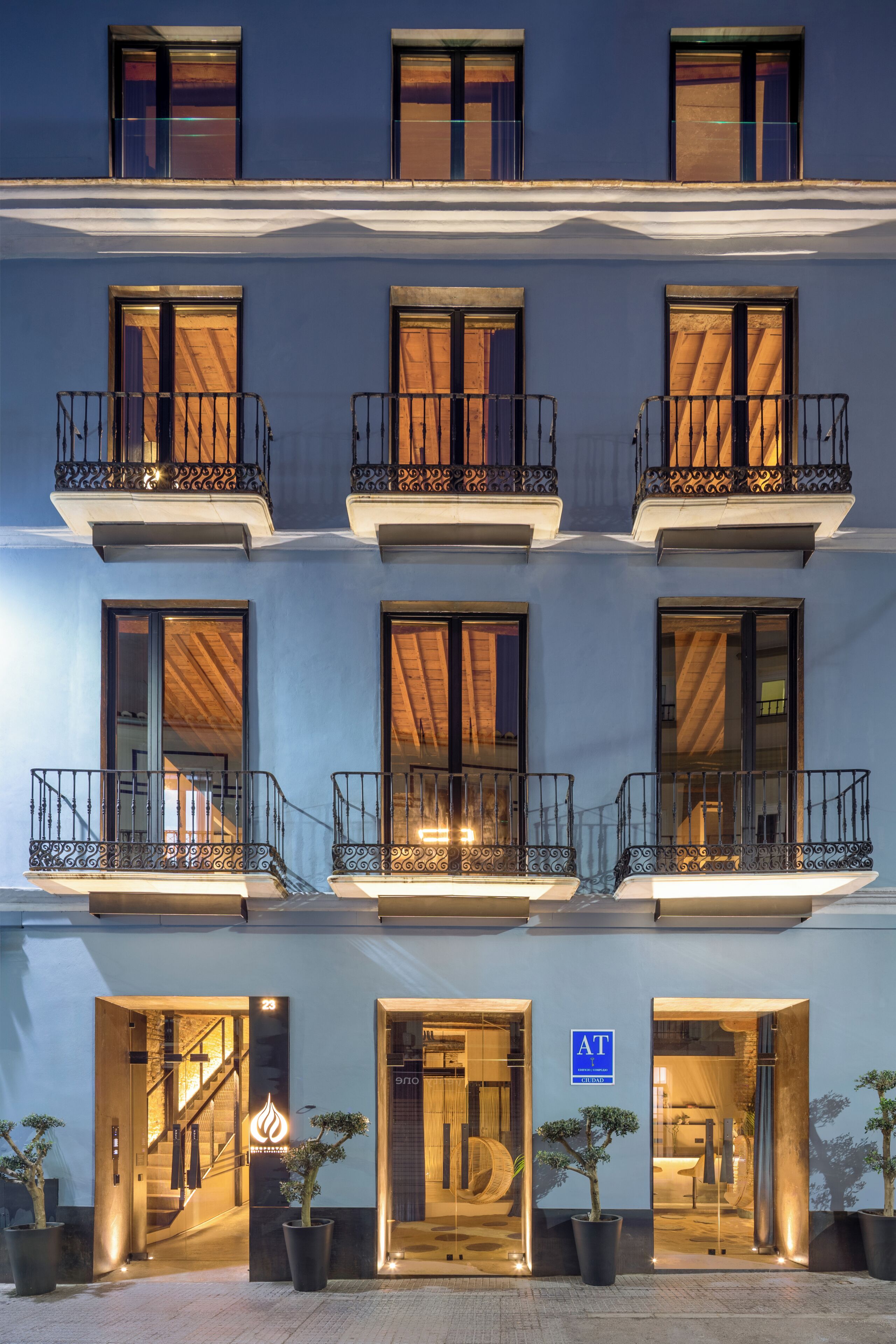 Un hotel de varios pisos con balcones, ventanas amplias y un letrero que indica que es un hotel.