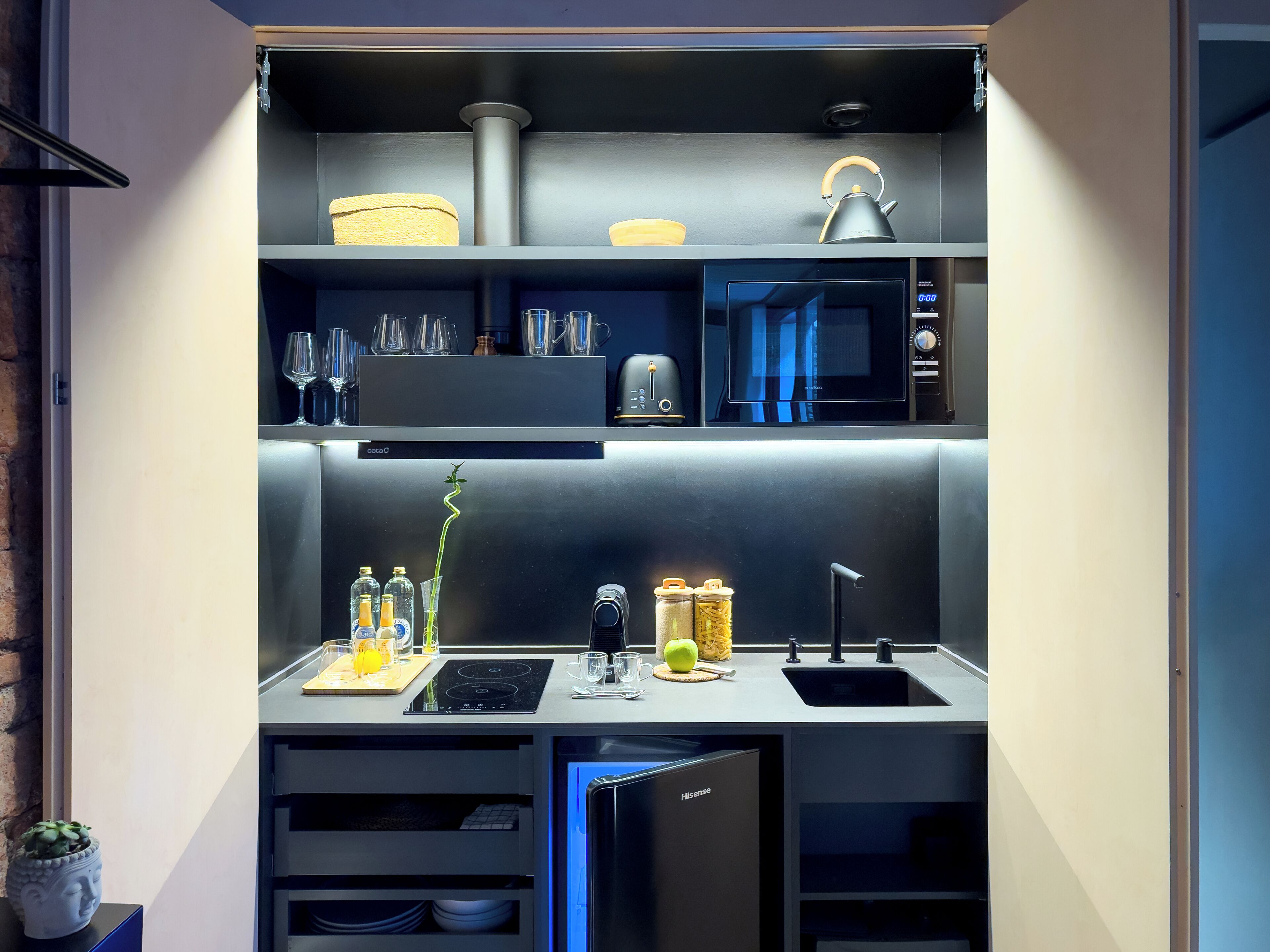 Una cocina compacta con horno empotrado, un lavamanos y un refrigerador pequeño.