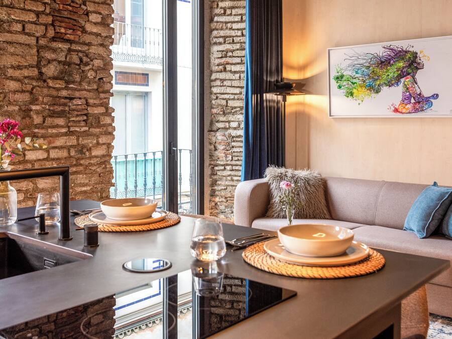 A modern dining area with a stone wall, a sofa, and a painting on the wall.