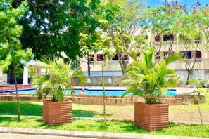 Un bâtiment doté d’une piscine, entouré de verdure et d’arbres.