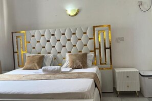 Une chambre d’hôtel bien rangée, avec un lit, des tables de chevet et un luminaire fixé au mur.
