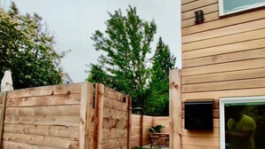 Une clôture en bois, un chemin en béton et un bâtiment avec une fenêtre et une porte.