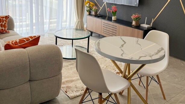 Un salon moderne comprenant un canapé, une table à manger, des chaises et un téléviseur fixé au mur.