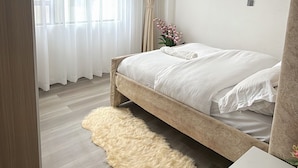 Une chambre à coucher avec un lit, un tapis moelleux, une table de chevet et une fenêtre avec des rideaux.