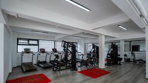 Une salle de sport équipée de tapis de course, d’appareils de musculation et d’un tapis rouge sur lequel est écrit le mot « APPROVISIONNEMENT ».