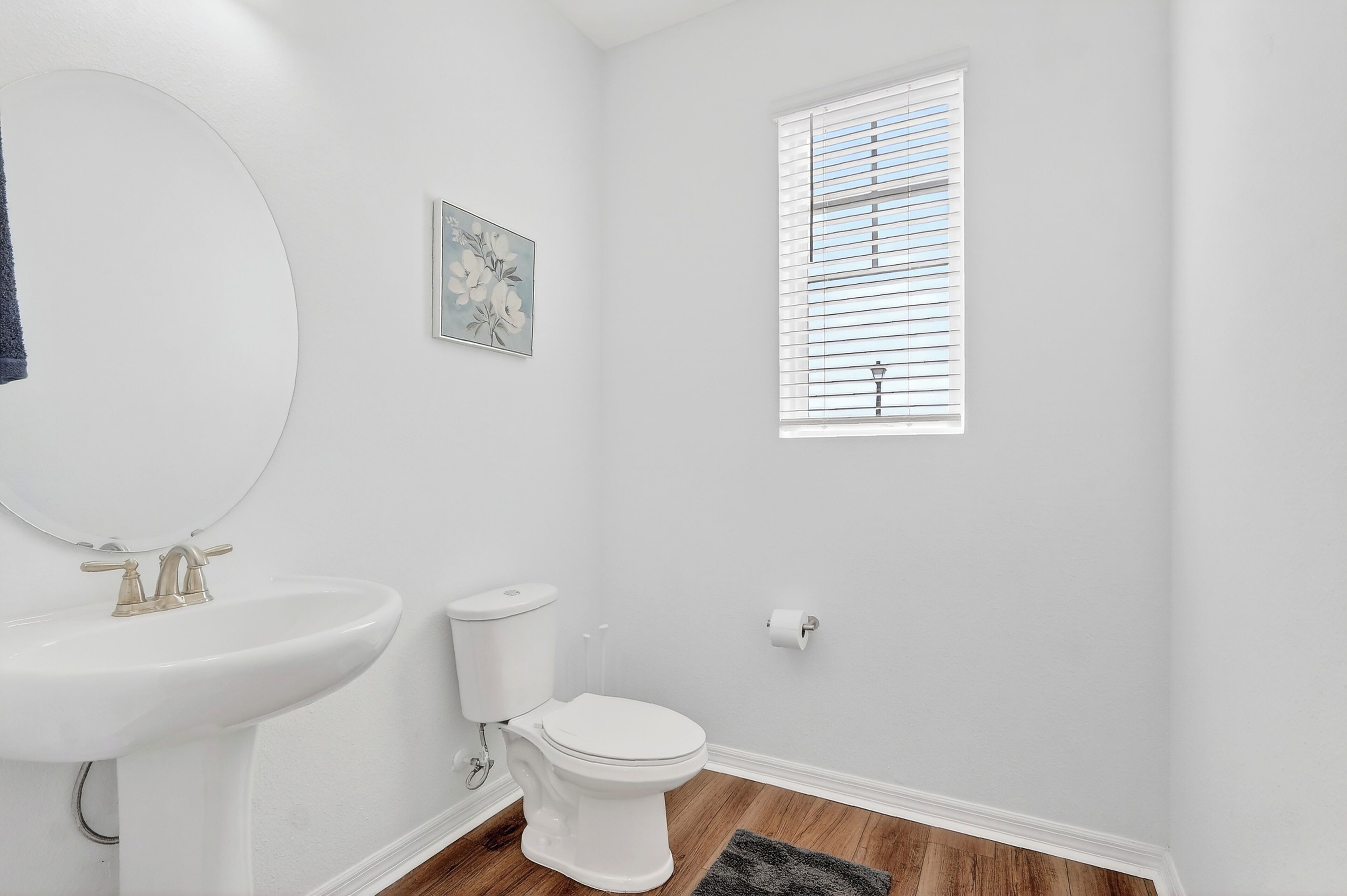 Ein Badezimmer mit Waschbecken, Toilette und Fenster mit Jalousien.