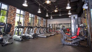 Une salle de sport équipée de tapis de course, de vélos elliptiques et d’appareils de musculation.