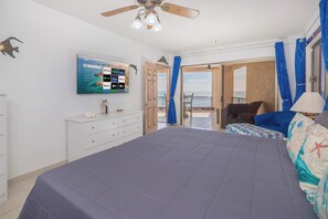 A bedroom with a bed, a TV mounted on the wall, a ceiling fan, and a view of the sea through an open door. - 3 Bedroom Beachfront at the Sonoran Spa W701 (Puerto Peñasco)