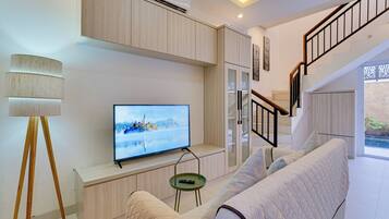 Una sala de estar moderna con una televisión de pantalla plana, un sofá, una lámpara y una escalera.