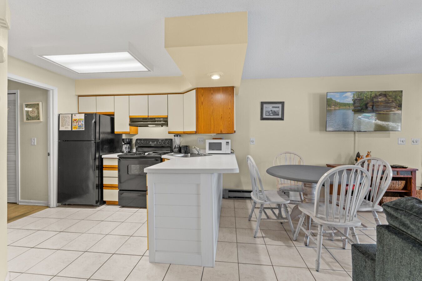 A compact kitchen with a central island, a dining area with chairs, and a microwave.