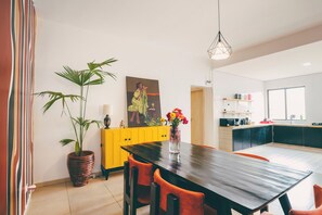 Eine moderne Küche mit einem Holztisch, Stühlen, einer Topfpflanze und einem Bild an der Wand.