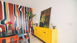 A dining area with a table, chairs, a yellow cabinet, a painting, and a vase with flowers. - THE TERRACE TOWNOUSE, a Creative Escape in the Heart of Kigali (Kigali)