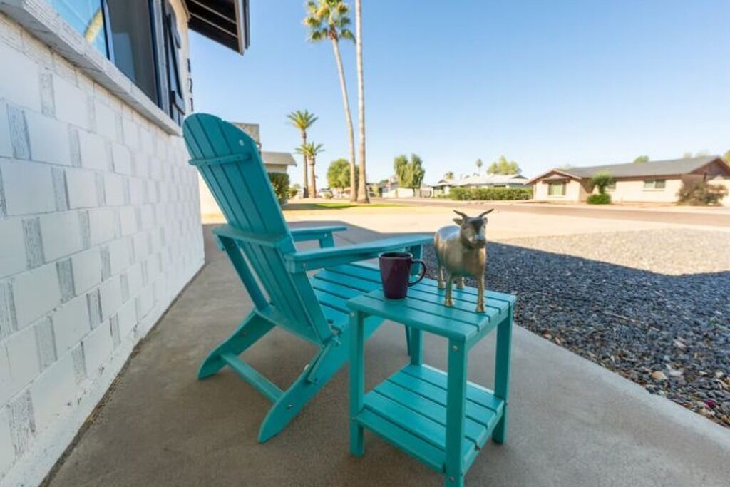 A turquoise chair and table set on a concrete patio with a metal sculpture on the table.