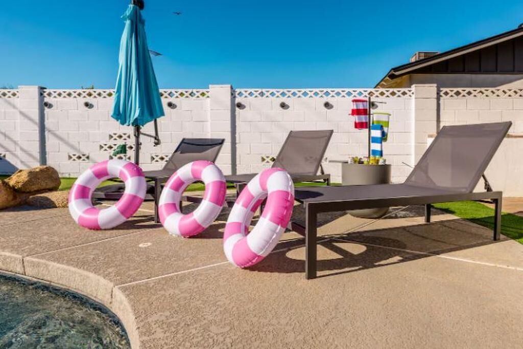 A poolside area with lounge chairs, a pool, and a decorative fence.