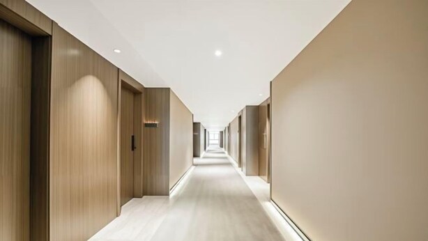 A long, narrow hallway with wooden doors on one side and plain walls on the other, leading to a bright end. - Lanting Hotel (Danyang)