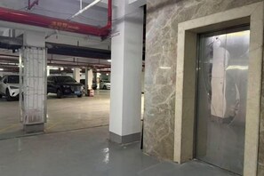 An indoor parking area with a marble wall and a door with a reflective surface. - Lanting Hotel (Danyang)