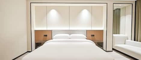A modern hotel room with a large bed, a sofa, and a mirror.