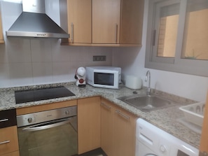 A compact kitchen with a microwave, toaster, coffee maker, and dishwasher.