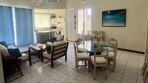 Un vaste espace de vie comprenant une table et des chaises de salle à manger, un canapé et deux ventilateurs de plafond.