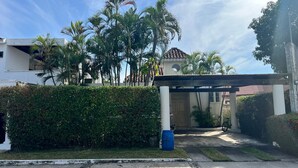 Un quartier résidentiel doté d’une entrée abritée, de palmiers et d’un bâtiment avec un toit en tuiles.