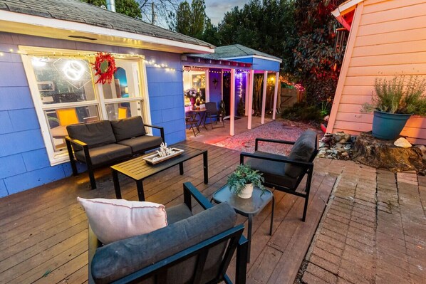A patio area with outdoor furniture, a covered seating area, and a house with blue siding.