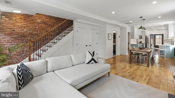 Un salon moderne avec un canapé blanc, un mur en briques et un escalier.