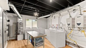 Een wasserette met industriële wasmachines, een metalen tafel en zichtbare leidingen.