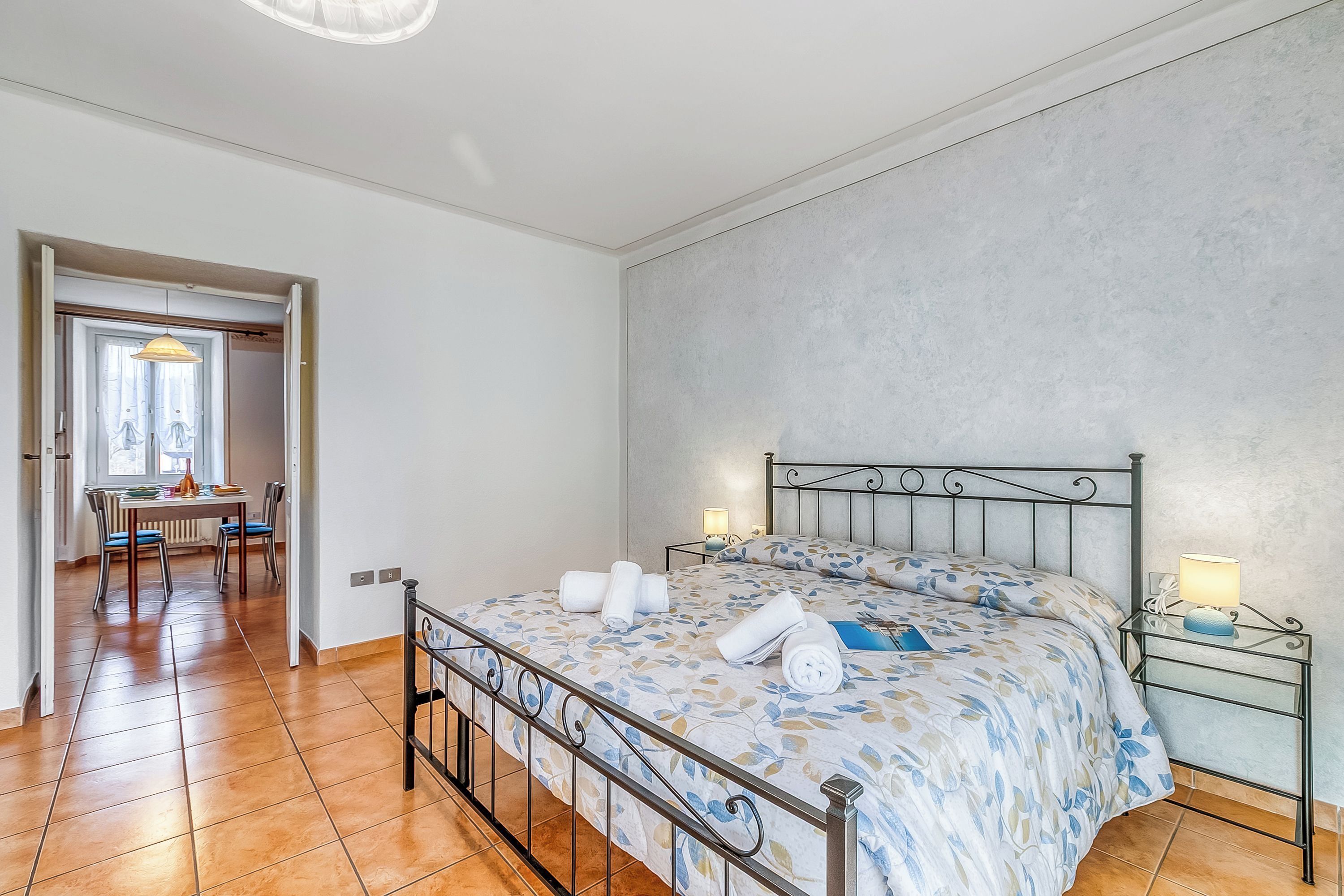 Una camera da letto con un letto, comodini, una sedia, un tavolo e una finestra.