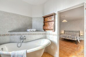 A bathroom with a freestanding bathtub, a vanity with a mirror, and a shower area. - Bee Apartment: Luino Lakeside With Outdoor Dining (Luino)