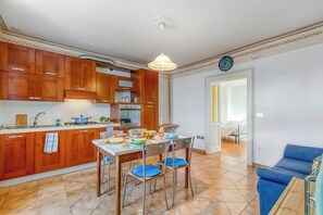 Eine moderne Küche mit Holzausbau, einem Esstisch mit Stühlen und einem blauen Sofa im Wohnbereich.