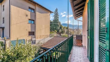 Un edificio residenziale con un balcone, un tetto in tegole e vista sul paesaggio circostante.