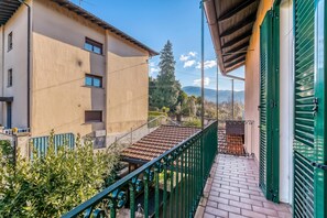 A residential building with a balcony, a tiled roof, and a view of the surrounding landscape. - Bee Apartment: Luino Lakeside With Outdoor Dining (Luino)
