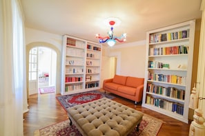A spacious room with a large bookshelf, a sofa, and a patterned rug. - Villa Nina - Luxury Villa With Pool in Salento (Zollino)