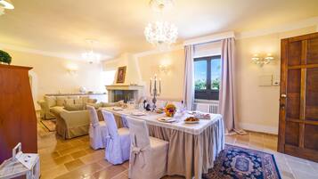 Un coin repas avec une table dressée pour quatre personnes, un lustre et une vue sur l’extérieur par une fenêtre.
