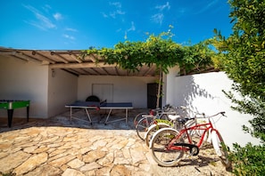 A courtyard with a ping pong table, a foosball table, and bicycles parked against a wall. - Villa Nina - Luxury Villa With Pool in Salento (Zollino)