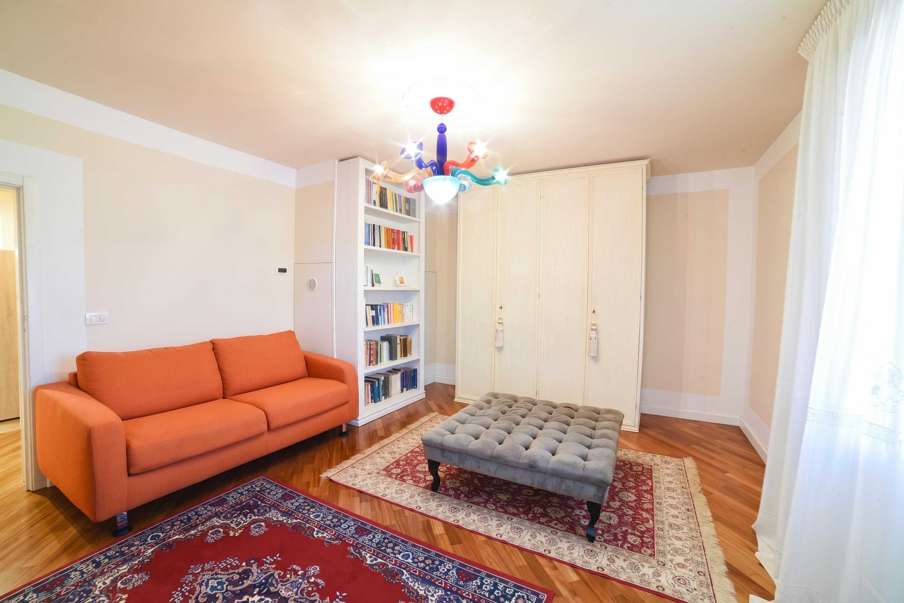 A living room with a sofa, ottoman, and a bookshelf.