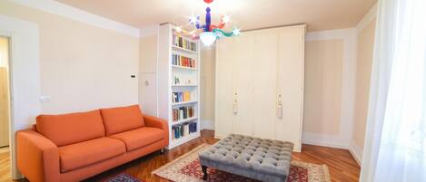 A living room with a sofa, ottoman, and a bookshelf.