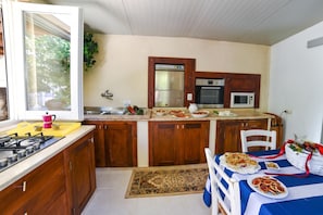 A compact kitchen with wooden cabinets, a gas stove, a sink, and a microwave. - Villa Nina - Luxury Villa With Pool in Salento (Zollino)