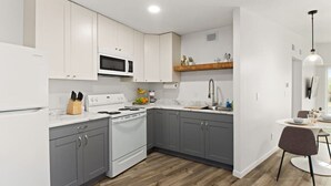 Eine moderne Küche mit weißen Schränken, einer Mikrowelle, einem Herd und einer Holz Arbeitsplatte.
